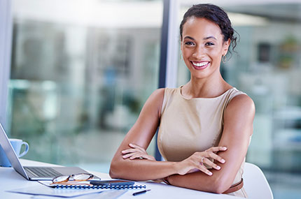 femeie zâmbitoare stând cu un laptop la un birou alb curat